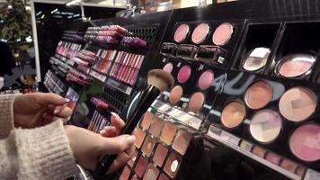 plank met cosmetica - lippenstift, oogschaduw - vrouw winkelen in een winkelcentrum video