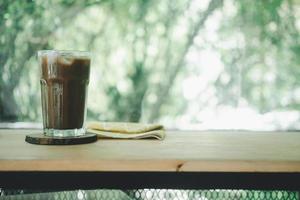 Iced mocha coffee in a tall glass on a wooden table. photo