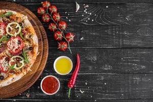 Traditional Italian pizza, vegetables, ingredients on a dark background photo