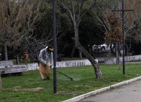 trabajadores que se dedican a cortar el césped con una desbrozadora en los parques municipales de la riviera de liguria en italia foto