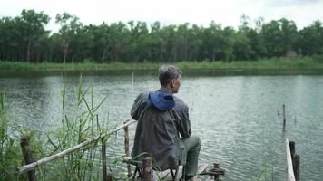 homem sênior segurando a pesca de anzol no rio video