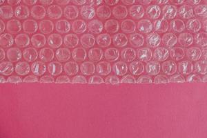 Packaging with air bubbles on a pink background. Bubble wrap texture, packaging, air bubble film. Top view. Copy, empty space for text photo
