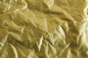 Crumpled gold foil as a background image. Top view. Copy, empty space for text photo