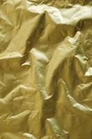 Crumpled gold foil as a background image. Top view. Copy, empty space for text photo