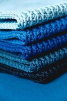 Stack of knitted material from threads of dark blue, light blue, gray colors on a blue background. Copy, empty space for text