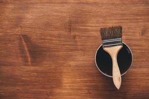 Paint brush on a jar with brown paint on a wooden background photo