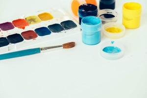 Colorful gouache paints and brush for painting on white background photo