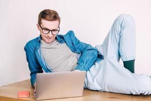 Man in shirt and glasses working on laptop computer sitting on table on a white background photo