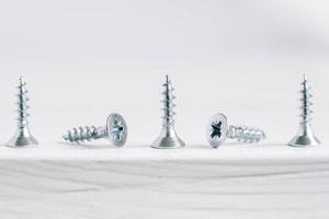 Metal tapping screws for wood on white wooden background. Construction equipment concept photo