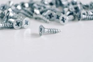 Metal tapping screws for wood on white wooden background. Construction equipment concept photo