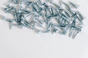 Metal tapping screws for wood on white wooden background. Construction equipment concept photo
