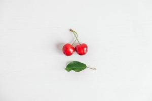 Fresh ripe cherries with green leav on the white wooden background. Top view. Copy, empty space for text photo
