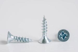 Metal tapping screws for wood on white wooden background. Construction equipment concept photo