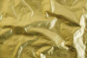 Crumpled gold foil as a background image. Top view. Copy, empty space for text photo
