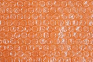 Packaging with air bubbles on a orange background. Bubble wrap texture, packaging, air bubble film. Top view. Copy, empty space for text photo