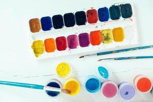 Colorful gouache paints and brush for painting on white background photo