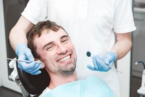 el dentista examina los dientes de un paciente masculino en la silla de un dentista