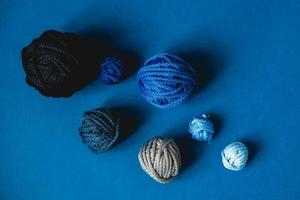 Balls of threads of dark blue, light blue, gray colors on a blue background. Top view. Copy, empty space for text photo