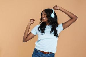 Smiling African woman dancing and singing with headphones on photo