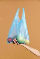 mujer sosteniendo una bolsa de basura de plástico con fruta
