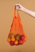 mujer sosteniendo una bolsa de fruta naranja reutilizable foto