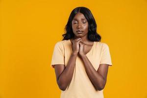 Calm African woman standing with closed eyes and hoping for something