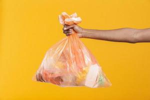 mujer africana sosteniendo una bolsa de basura de plástico naranja foto