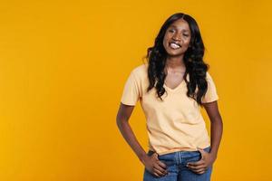 mujer africana feliz en camiseta cogida de la mano en los bolsillos foto