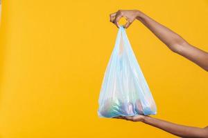 mujer africana sosteniendo una bolsa de basura de plástico azul con fruta foto