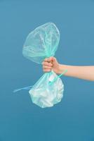 Young woman's arm holding plastic trash bag photo