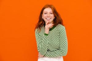 Young ginger woman in plaid sweater laughing at camera