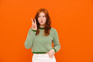 Ginger young woman in plaid sweater showing peace sign photo