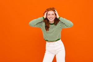 Young woman with ginger-colored hair in plaid sweater laughing at camera photo