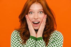 Excited ginger woman in plaid sweater expressing surprise at camera