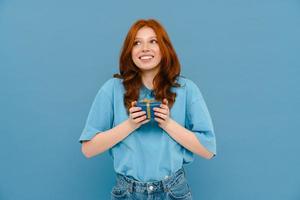 mujer joven con camiseta sonriendo mientras posa con caja de regalo foto
