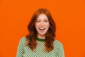 Young ginger-haired woman in plaid sweater smiling and winking photo