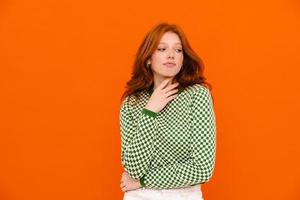 Young woman with ginger hair in plaid sweater looking aside photo