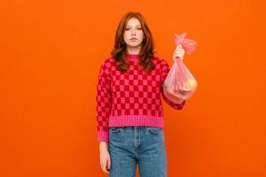 Young woman wearing a plaid sweater holding a plastic trash bag photo