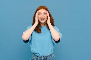 Excited ginger woman wearing t-shirt expressing surprise at camera photo