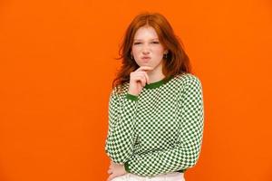 Displeased ginger woman in plaid sweater frowning at camera photo