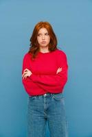 Sad ginger-haired woman wearing red sweater looking to the side photo