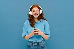 mujer joven de jengibre en camiseta usando teléfono celular y auriculares foto