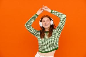 Happy ginger woman in plaid sweater dancing with headphones