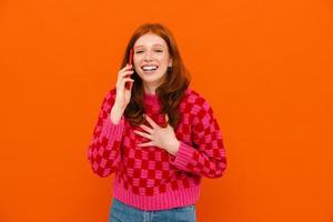 Ginger woman in plaid sweater laughing and talking on cellphone