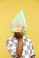 Man holding plastic trash bag with fruit in front of face photo