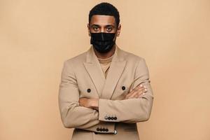 Serious African businessman in protective face mask looking at the camera photo