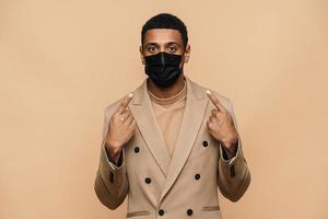 Serious African businessman showing his protective face mask photo