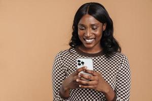 Cheerful African woman texting by phone photo