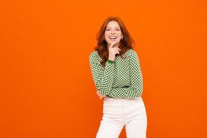 Young smiling ginger-haired woman in plaid sweater laughing at camera photo