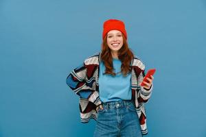 Smiling ginger woman in multicolored sweater using cellphone